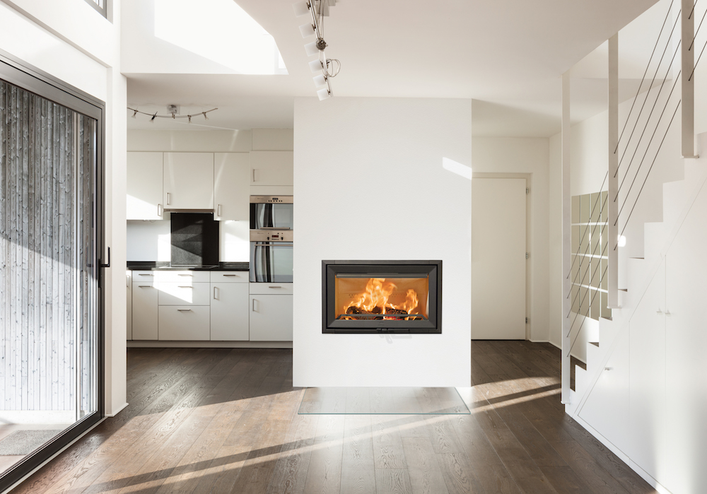 Grote gietijzeren inbouwhaard uit Noorwegen. Jotul I 620 staat hier mooi als scheidingswand tussen keuken en andere ruimte. #inbouwhaard #houthaard #houtopslag