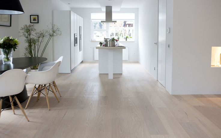 Open witte woonkeuken met kookeiland en doorgetrokken houten vloer van Uipkes