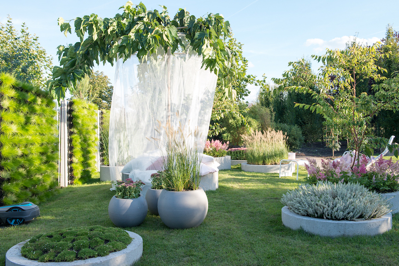 Tuintrend 2019 - In de tuin ‘Soft Landing’ zie je daarom veel ronde vormen, lekkere kussens en aaibare beplanting. Een groene plek waarin je heerlijk tot rust kunt komen en die je het gevoel geeft dat je door een enorm kussen wordt opgevangen. In deze trendtuin tuin overheersen vriendelijke pasteltinten. Het gazon speelt een belangrijke rol. Niet alleen een plek om met blote voeten te betreden maar ook praktisch: regenwater zakt, in tegenstelling tot een betegelde tuin, direct weg in de bodem #tuintrend #trendtuin #tuininspiratie #tuinen #groen #tuinplanten #tuinidee #2019